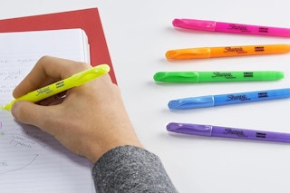 a person highlighting a piece of paper with colorful Sharpies