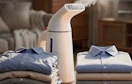 a portable steamer next to a pile of folded shirts 