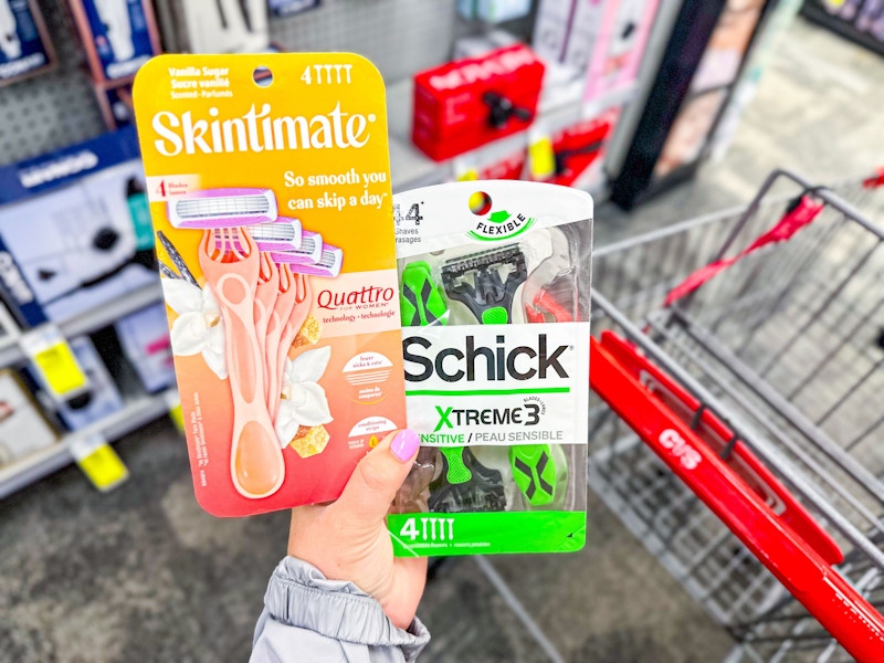 person holding schick and skintimate razor packs over a cvs cart