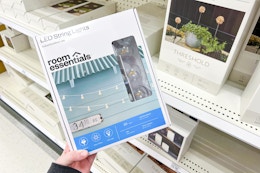 hand holding a box of led outdoor string lights in front of a target shelf
