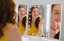 a person doing their makeup in a tri-fold mirror
