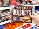 a person holding hersheys in store by cart