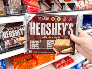 a person holding hersheys in store by cart