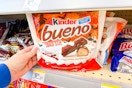 person grabbing a bag of kinder bueno chocolate bars off a shelf