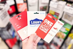 person holding under armour, lowes, and chilis gift cards