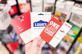person holding under armour, lowes, and chilis gift cards