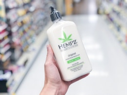 a hand holding a bottle of lotion in a store aisle