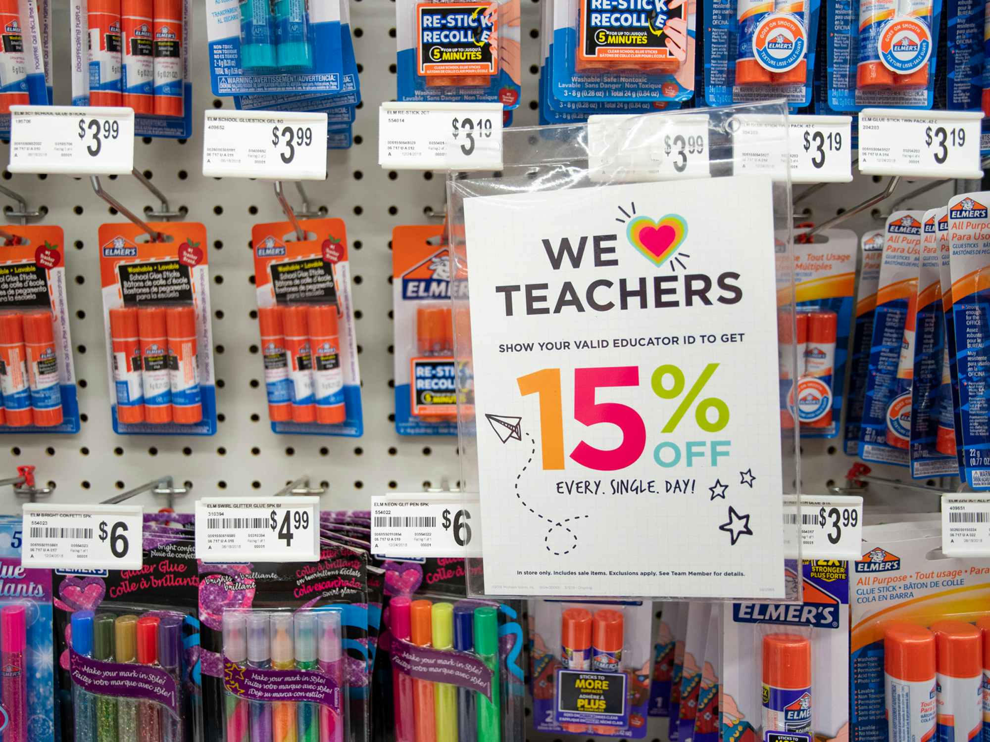 A sign on a wall display at Michaels that says "We love teachers" offering 15% off every day with a valid educator ID.