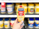 hand holding hellman's spicy mayo in front of a target shelf