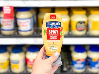 hand holding hellman's spicy mayo in front of a target shelf