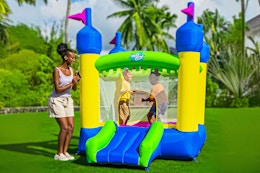 Lifestyle image of the H2OGO! Castletopia Inflatable Bounce House (outdoor setting with adult + 2 children)