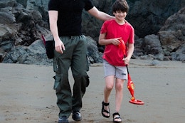 a child using a metal detector on a beach