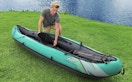 a person next to a teal kayak on a lake 
