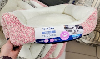 hand holding a pink tweed dog bed