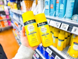 hand holding two yellow Neutrogena beach defense sunscreen