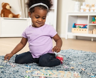 a little girl playing with a wooden puzzle