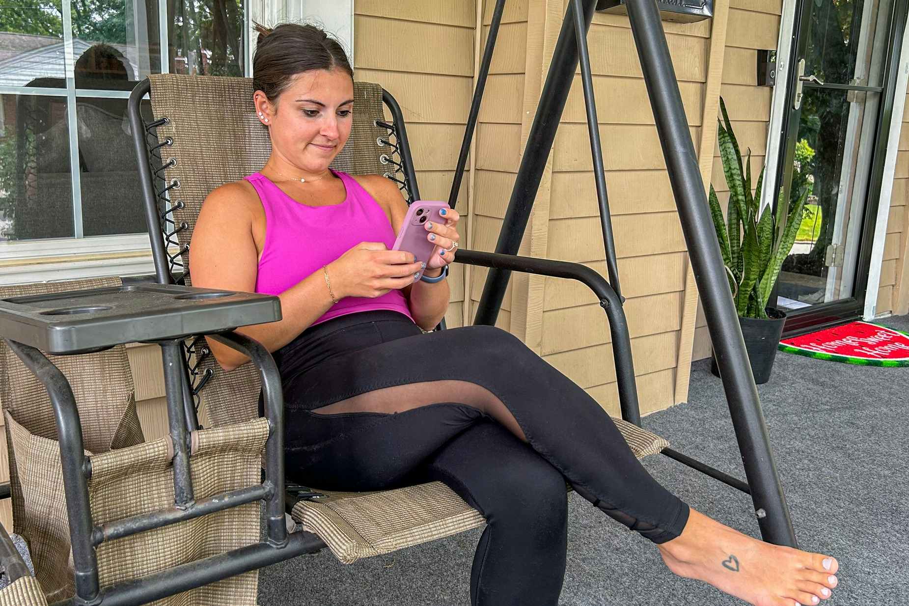 a person holding an iphone while sitting on a porch swing