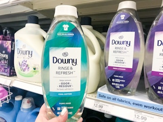 hand holding one bottle of Downy rinse and refresh in front of display