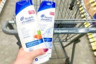 hand holding two bottles of head & shoulders next to a walgreens shopping cart