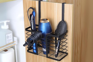 A basket hangs on a cabinet door in the bathroom to hold hair tools.