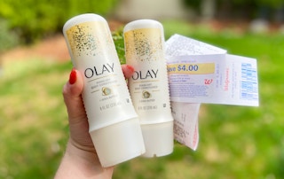 hand holding two bottles of Olay rinse-off body conditioner with a walgreens receipt and register reward