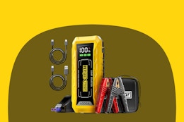 A yellow rectangular jump starter has a red clamp and a black clamp for use on a car battery. It also has 2 USB cables included.