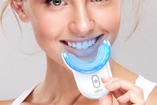 woman holding teeth whitening kit and smiling