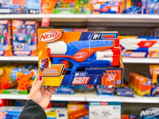 hand holding a nerf agility blaster in front of toys on a target shelf