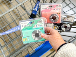 hand holding a mint colored camera with two other cameras in the background