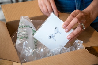 A person taking a box of Apple Airpod Pros out of a delivery box.