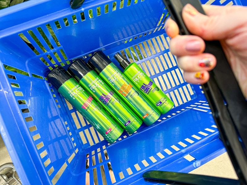 hand holding walmart cart with four garnier fructis style hairspray bottles