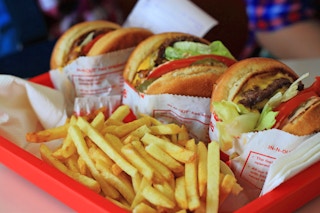 A tray of three burgers and some french fries on a table at In-N-Out.