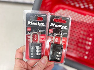 hand holding 2 master lock padlocks in front of a target cart