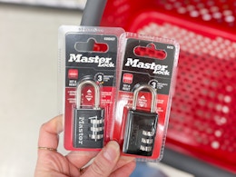 hand holding 2 master lock padlocks in front of a target cart