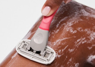 a person shaving with a pink razor