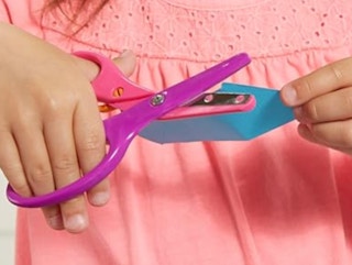 child using training scissors to cut paper