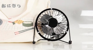 a mini usb powered portable fan in black next to a white bag