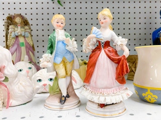 vintage boy and girl porcelain figurines on thrift store shelf