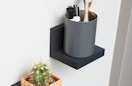 a cup of markers on a display ledge on a wall