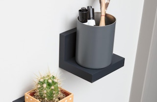 a cup of markers on a display ledge on a wall