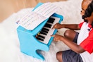 Lifestyle image of the Melissa & Doug toy piano being played with by a child on a plush rug