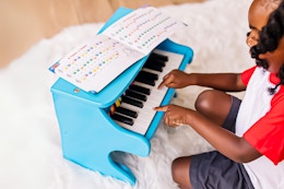 Lifestyle image of the Melissa & Doug toy piano being played with by a child on a plush rug