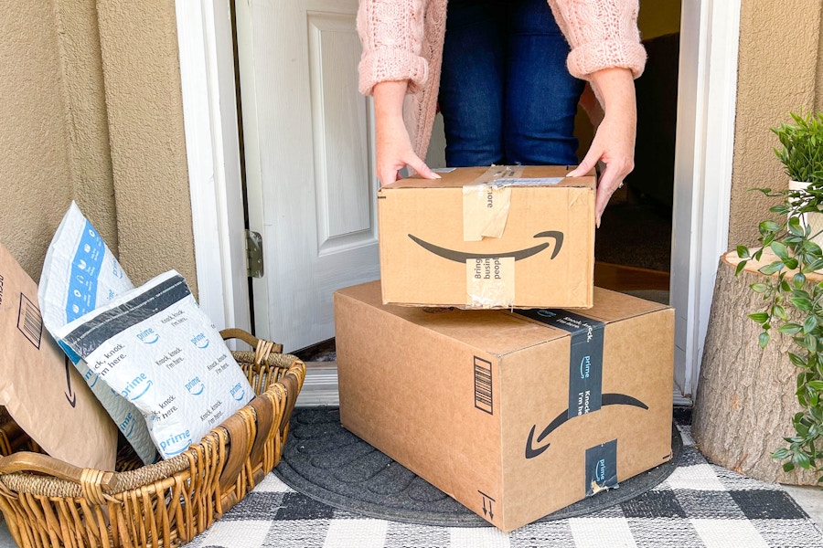 a person picking up amazon boxes next to a basket with packages on front porch