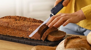a person using an electric knife to cut a loaf of bread