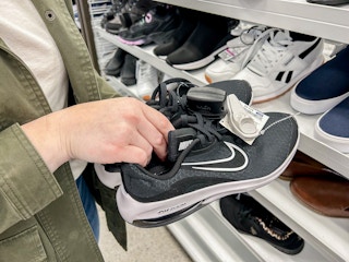 a person holding up nike shoes in ross