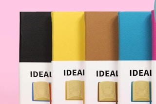 a stack of colorful notebooks on a pink background