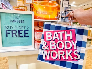 hand holding bag in front of 3-wick candle display