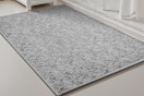 A heather grey low-pile bathmat sits in front of a white marble shower