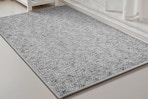 A heather grey low-pile bathmat sits in front of a white marble shower