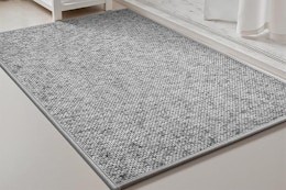 A heather grey low-pile bathmat sits in front of a white marble shower